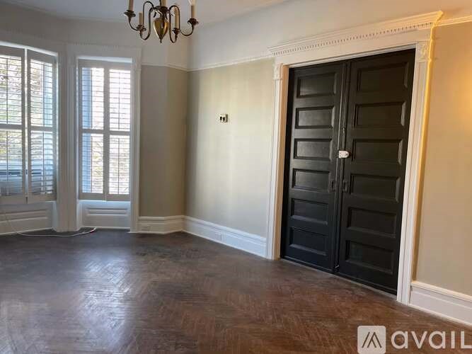 A room with a chandelier, a door, and a window.