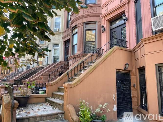 A row of brown houses with black railings and steps leading to the front doors.