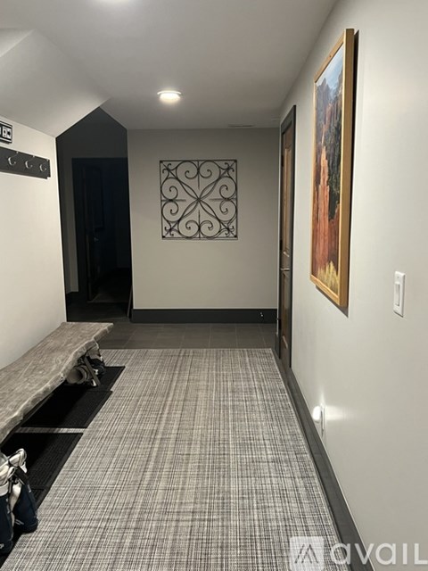 A hallway with a bench and a painting on the wall.