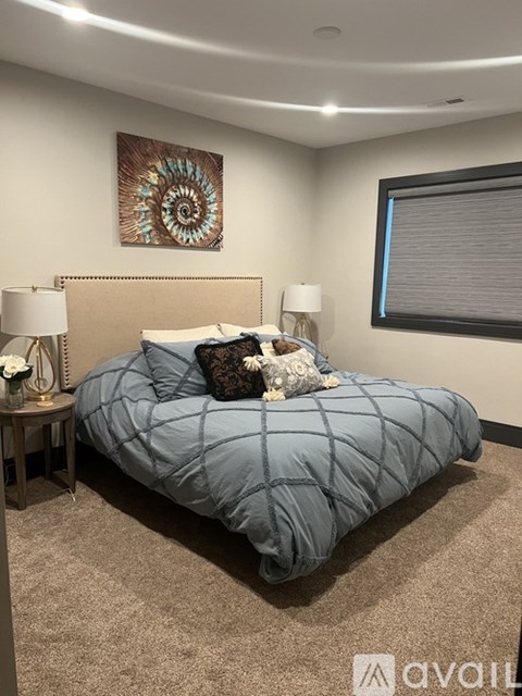 A bed with a blue comforter and a white pillow is in the center of the room.