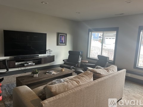 A living room with a brown couch, a coffee table, and a flat screen TV.