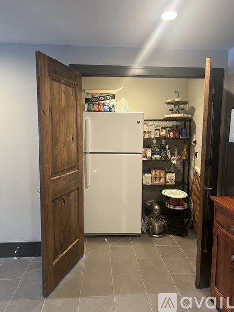 A white refrigerator is in a kitchen with a wooden door.