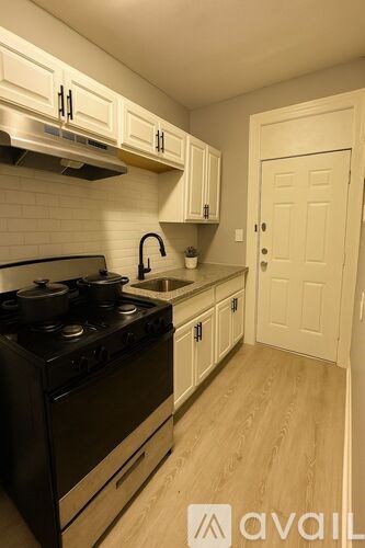 A kitchen with a black stove top oven and white cabinets.