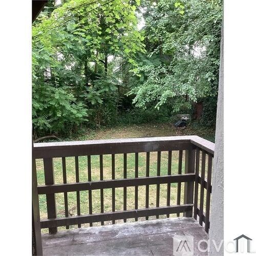 A wooden deck with a railing overlooking a lush green forest.