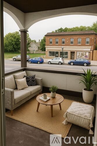 A patio with a couch, coffee table, and potted plant overlooks a street.