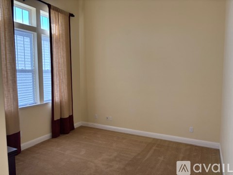 A room with beige walls and a window with curtains.