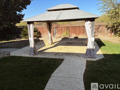 A gazebo in a garden with a stone pathway leading to it.