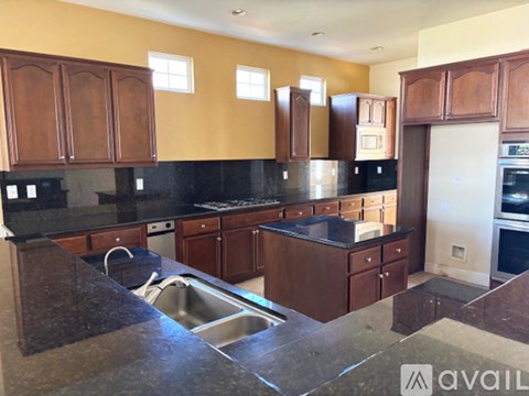 A kitchen with brown cabinets and black countertops.