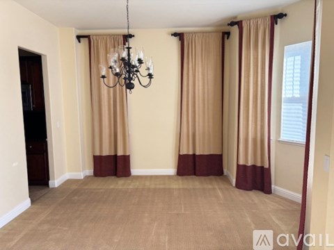 A room with a chandelier and curtains.