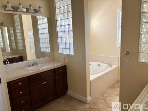 A bathroom with a tub, sink, and mirror.