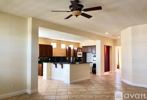 A kitchen with a black counter top and a ceiling fan.