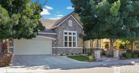 A house with a stone facade and a garage door is for sale.