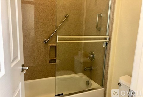 A bathroom with a glass shower door and a white tub.