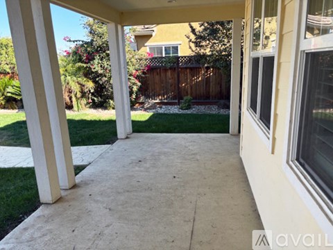 A patio with a white railing and a concrete floor.