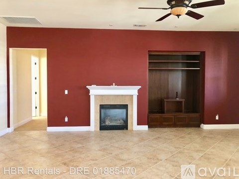 A living room with a fireplace and a ceiling fan.