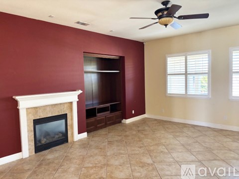 A living room with a fireplace and a ceiling fan.
