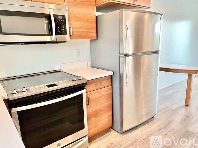 A kitchen with a stainless steel refrigerator, microwave, and oven.