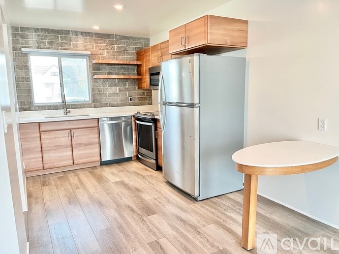 A kitchen with a refrigerator, oven, and table.