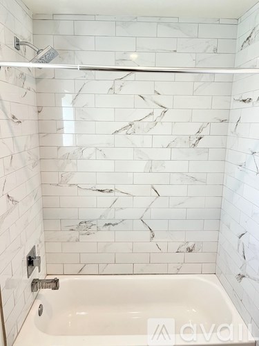 A white marble tiled bathroom with a white bathtub.