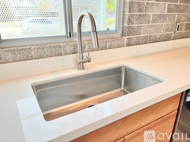 A kitchen sink with a chrome faucet and a window in the background.