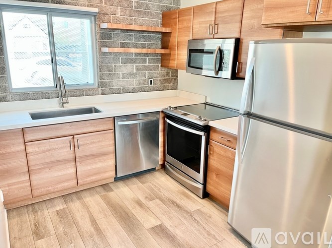 A kitchen with a refrigerator, oven, microwave, and sink.