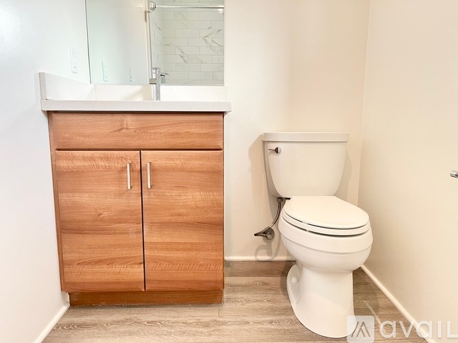 A white toilet sits next to a wooden cabinet in a bathroom.