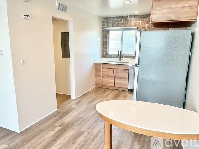 A kitchen with a refrigerator, wooden table, and cabinets.