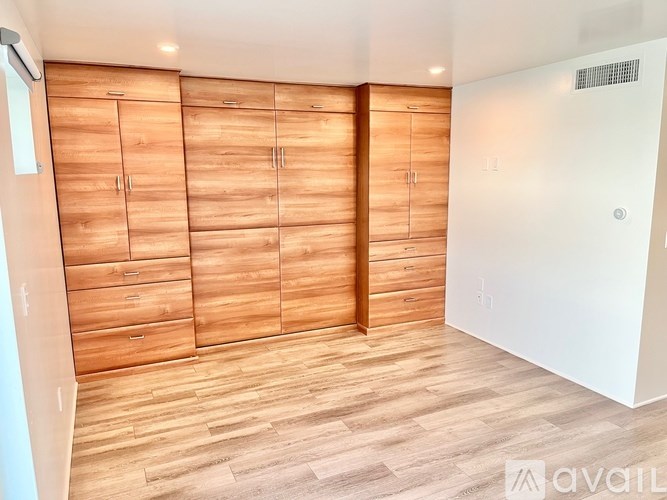 A room with wooden floors and a wall of wooden cabinets.