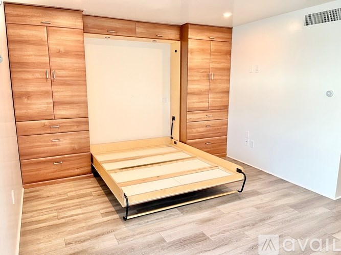 A bedroom with a bed, wooden cabinets, and a white door.