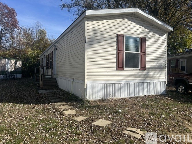 A mobile home with a white siding and red window trim.