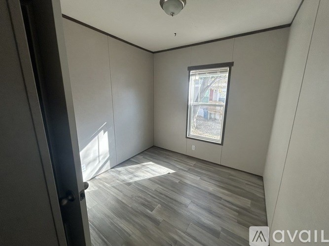 A room with a window and wooden flooring.