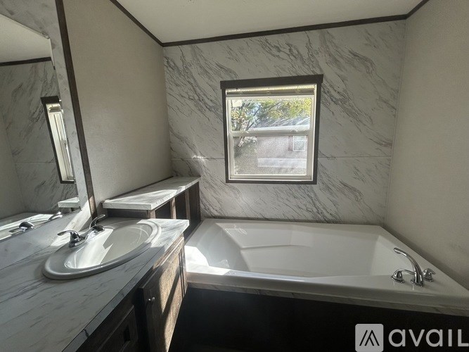 A bathroom with a marble wall and a large tub.