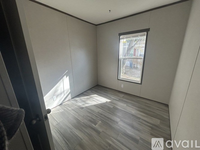 A room with a window and wooden flooring.