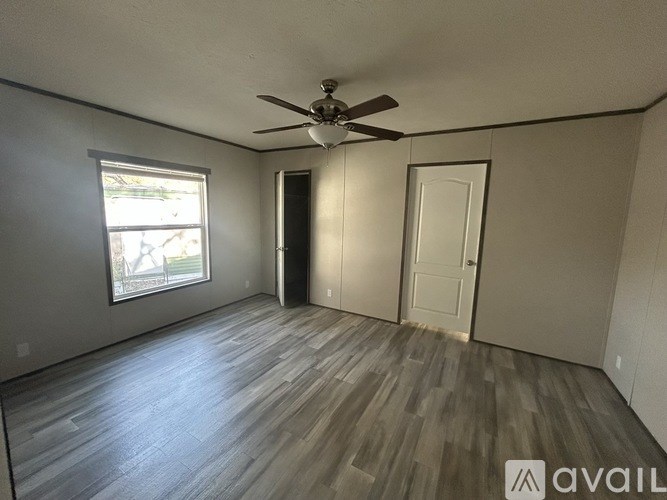 A room with a ceiling fan and wooden flooring.