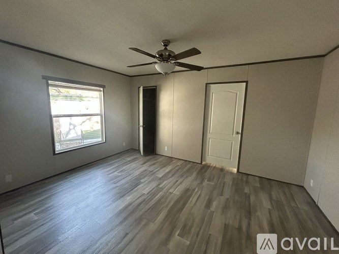 A room with a ceiling fan and wooden flooring.