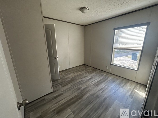 A room with a wooden floor and a window with blinds.