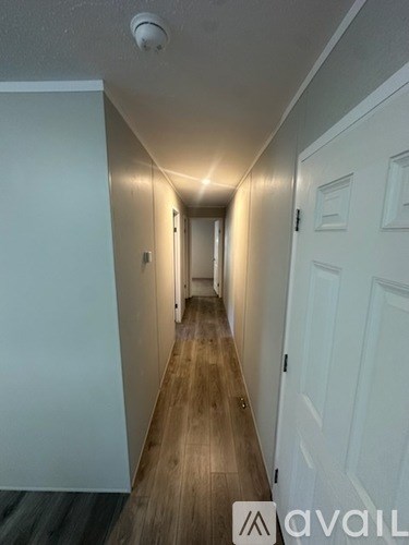 A long hallway with white doors and wooden floors.