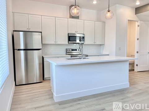 A kitchen with white cabinets and a stainless steel refrigerator.