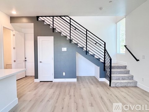 A modern staircase with a black metal railing leads up to a landing with a white door.
