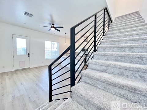 A staircase with a metal railing and a ceiling fan.