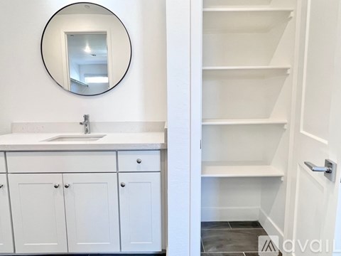 A bathroom with a white sink and a round mirror.