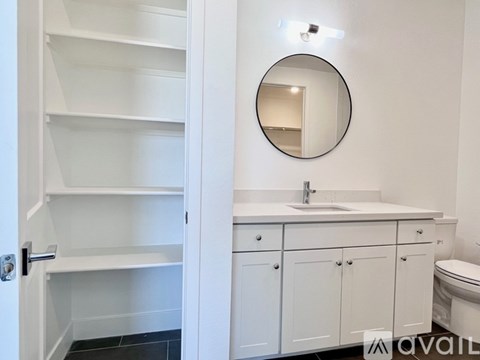 A bathroom with a white sink and a round mirror.