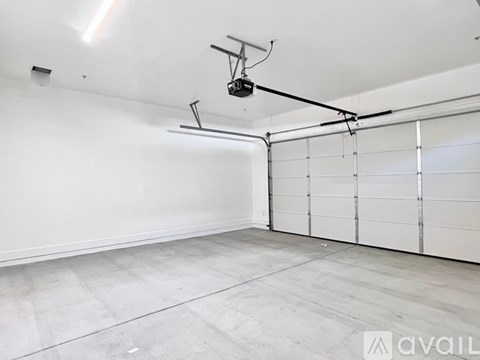 A large empty room with a garage door on the side.