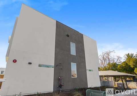 A modern building with a white and grey exterior and a red circular object on the wall.