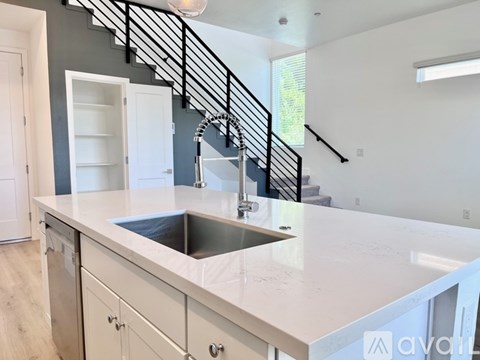 A kitchen with a white countertop and a stainless steel sink.