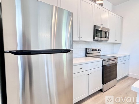 A kitchen with a stainless steel refrigerator and white cabinets.