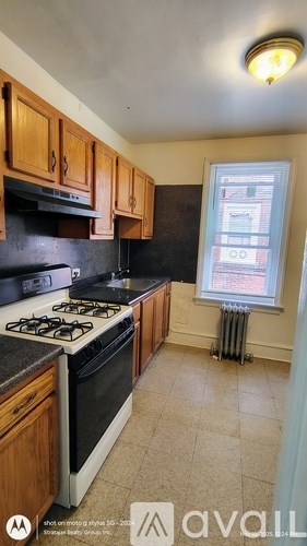 A kitchen with a white stove top oven and black countertops.