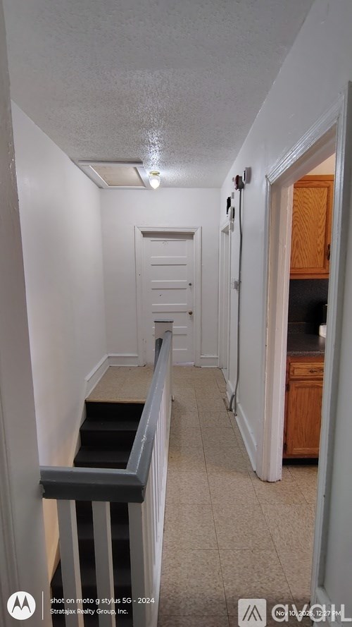 A hallway with a staircase and a door on the right.