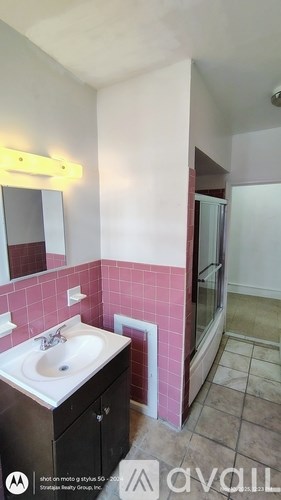 A bathroom with pink tiles and a sink.