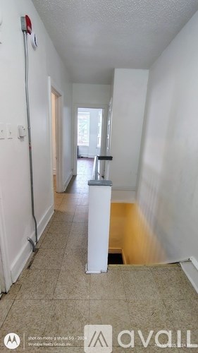 A long hallway with a white wall and a door at the end.